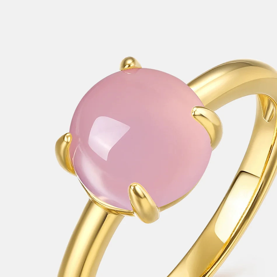 Bague en or avec pierre ronde de quartz rose, mise en valeur sur fond clair.